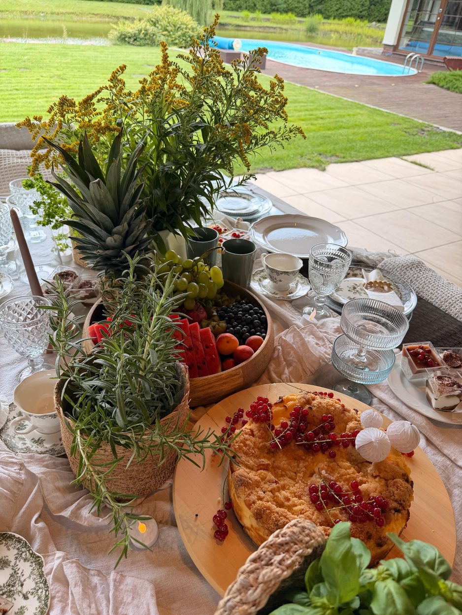 Stół zastawiony latem, w tle basen i staw
